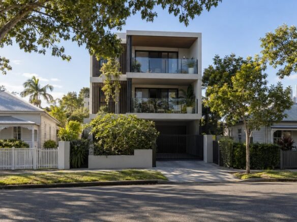 New three-storey apartment building rising between older single-storey cottages on a Brisbane residential street