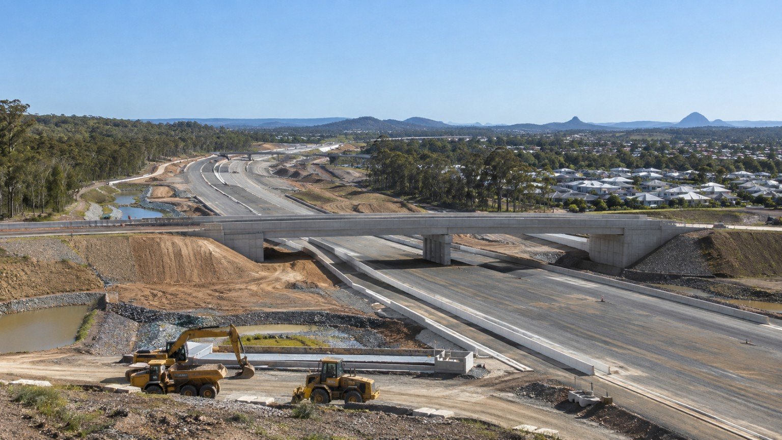 New motorway and arterial road infrastructure under construction beside a growing northern Gold Coast community