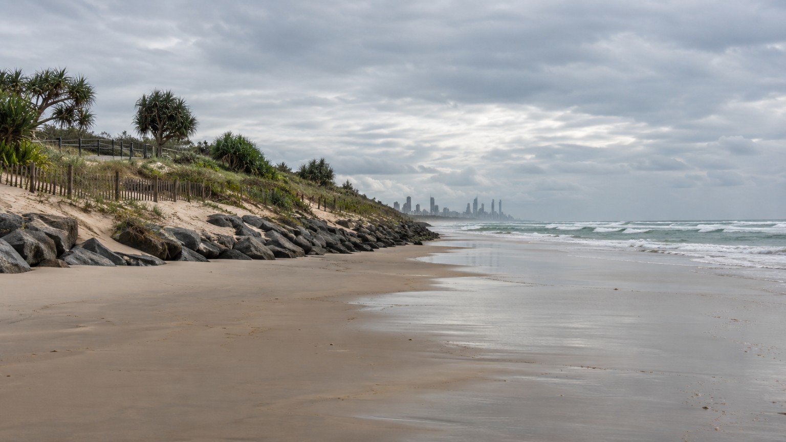 Gold Coast beach with a rock seawall, restored dune vegetation and sand fencing along the foreshore