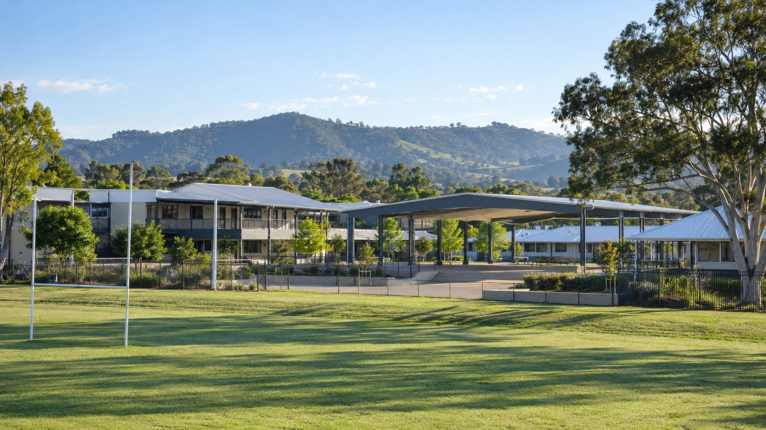 Contemporary Queensland school buildings with covered walkways and sports field in a growing western community
