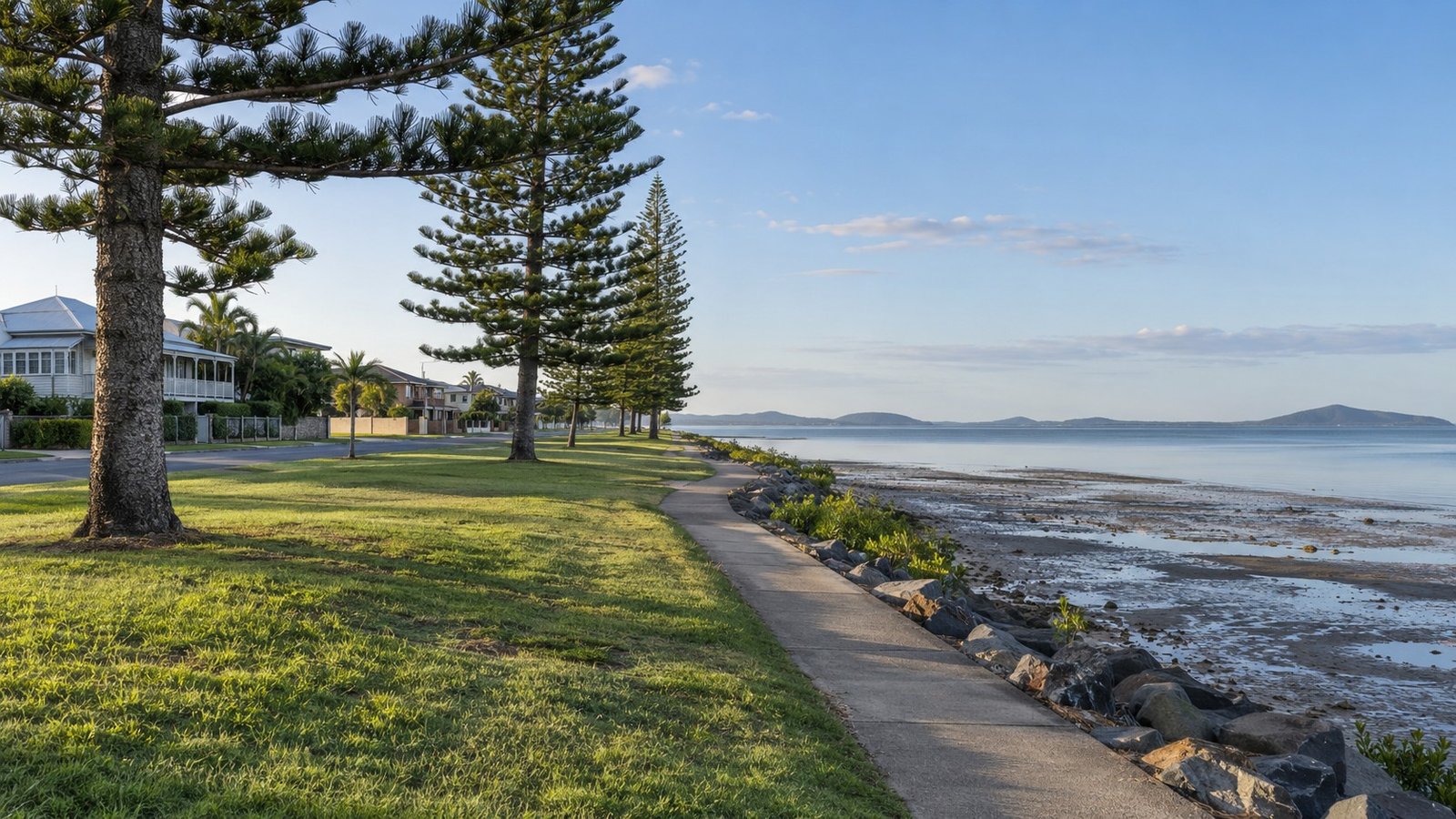 Calm bayside foreshore reserve with Norfolk pines and a waterfront path in south east Queensland